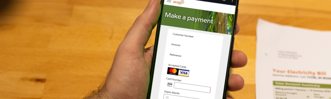 person holding phone with Jacana Energy payment webpage on screen